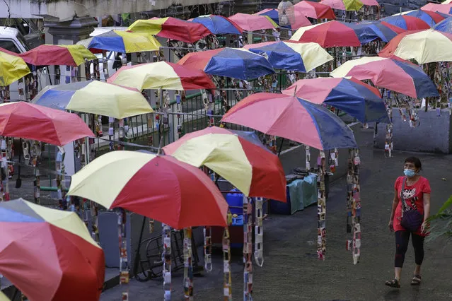 A woman wearing a face mask to help curb the spread of the coronavirus walks under decorative umbrellas in Taguig, Philippines on Tuesday, January 26, 2021. (Photo by Aaron Favila/AP Photo)