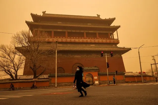 A woman walks past Drum Tower during morning rush hour as Beijing, China, is hit by a sandstorm, March 15, 2021. (Photo by Thomas Peter/Reuters)