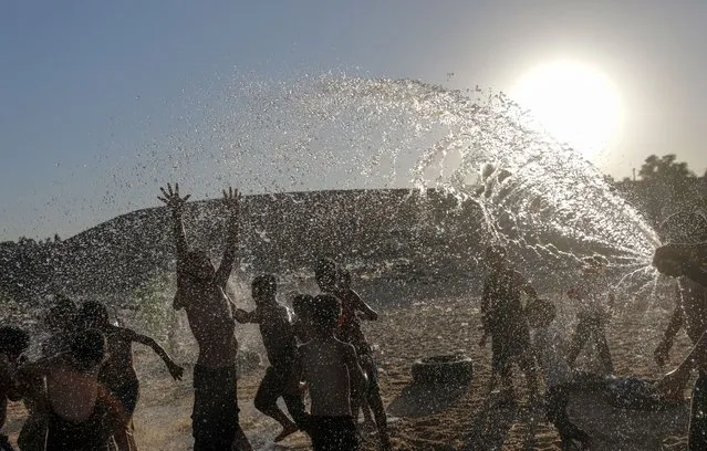 Palestinian refugee children cool off with sprayed water during hot weather in a slum on the outskirts of Khan Younis refugee camp, Gaza Strip, 19 July 2023. Temperatures reached 34 degrees Celsius on 19 July. (Photo by Mohammed Saber/EPA/EFE/Rex Features/Shutterstock)