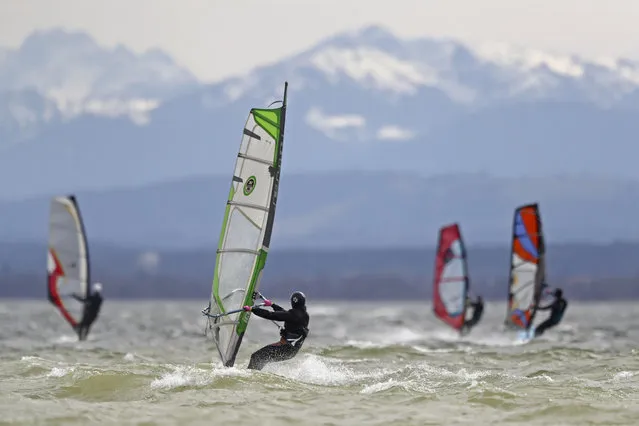 Surfers brave high winds to speed on the waves at lake Ammersee in front of the Alps near Herrsching, Germany, Monday, April 5, 2021. (Photo by Matthias Schrader/AP Photo)