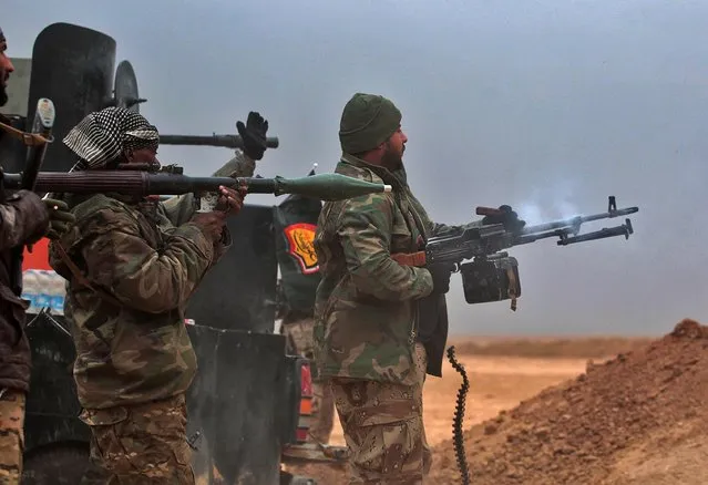 Iraqi Shiite fighters from the Hashed al- Shaabi (Popular Mobilisation) paramilitaries fire at an Islamic State group target as they advance near the village of Tal Abtah, south of Tal Afar, on November 30, 2016, during a broad offencive by Iraq forces to retake the city Mosul from IS jihadists. (Photo by Ahmad Al- Rubaye/AFP Photo)