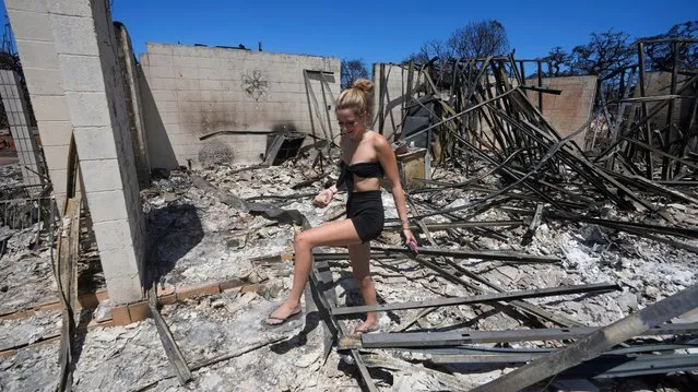 Sydney Carney walks through her home, which was destroyed by a wildfire, Friday, August 11, 2023, in Lahaina, Hawaii. (Photo by Rick Bowmer/AP Photo)