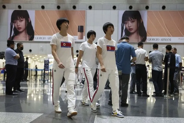 North Korean women wearing track suits with the North Korean flag walk near advertisement featuring Hanni, a K-Pop star from the group Black Pink, after checking in for a flight to Astana at the Capital Airport in Beijing, Friday, August 18, 2023. A team of North Korean Taekwondo athletes are reportedly travelling via China to Astana, capital of Kazakhstan, to compete in a Taekwondo competition. (Photo by Ng Han Guan/AP Photo)