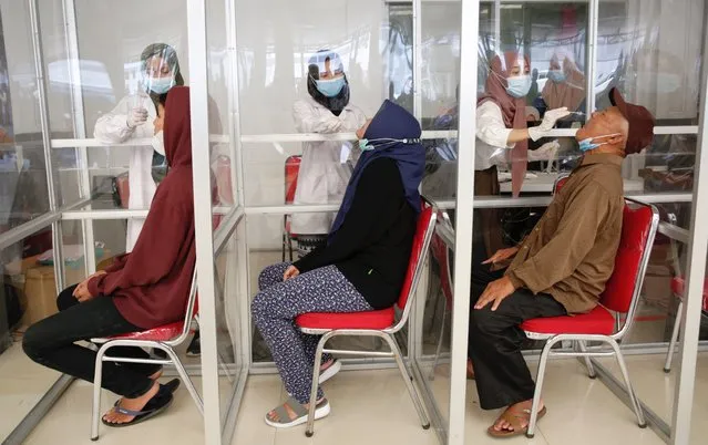 Healthcare workers collect samples during a COVID-19 swab test for train passengers ahead of Eid al-Fitr holidays at Pasar Senen Train station in Jakarta, Indonesia, 05 May 2021. The Indonesian government strictly prohibits people from carrying out Eid homecoming activities this year to protect the community from the transmission of the coronavirus from 06 to 17 May 2021. (Photo by Adi Weda/EPA/EFE)