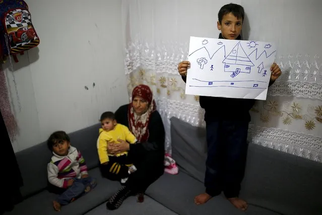 Syrian refugee Ahmet Cemal, 12, shows a drawing of home as his mother and his two brothers sit next to him in their tent in Nizip refugee camp in Gaziantep province, Turkey, December 13, 2015. (Photo by Umit Bektas/Reuters)