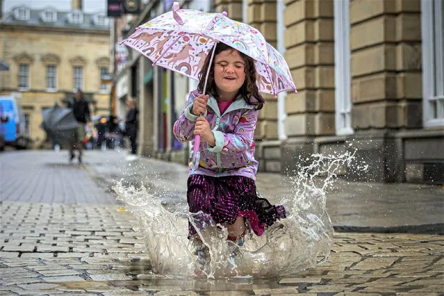 Four-year-old Eve Hill enjoys the wet weather in York, northeast England on August 2, 2023. (Photo by James Glossop/The Times)
