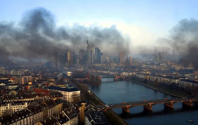 A handout picture made available by www.mainhattan-webcam.de shows black smoke billowing over the skyline of the financial metropolis of Frankfurt, Germany, 18 March 2015. German authorities arrested about 300 people in Frankfurt amid violent anti-austerity protests at the opening of a new headquarters for the European Central Bank (ECB), police said. (Photo by EPA/Mainhattan-Webcam.de)
