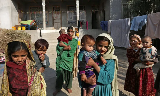 In this Monday, November 30, 2015 photo, internally displaced girls hold babies after their family left their village in Behsood district of Jalalabad east of Kabul, Afghanistan. It is a makeshift camp with thousands of people who left their homes to escape what is turning out to be an increasingly vicious war for control of the region between the Taliban and fighters of Afghanistan's Islamic State group affiliate. (Photo by Rahmat Gul/AP Photo)