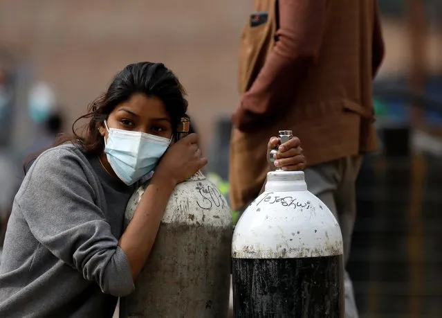 A woman holds on to the oxygen cylinders for a patient after refiling them at a factory, amidst the spread of coronavirus disease (COVID-19) surge as India's outbreak spreads across South Asia, in Kathmandu, Nepal on May 9, 2021. (Photo by Navesh Chitrakar/Reuters)