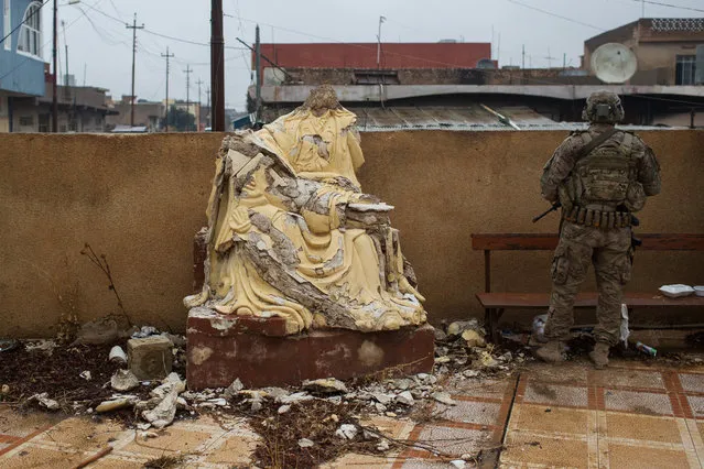 A soldier from the U.S Army stands guard next to a defaced christian statue during Christmas Day mass at Mar Hanna church in Qaraqosh on December 25, 2016 in Mosul, Iraq. (Photo by Chris McGrath/Getty Images)