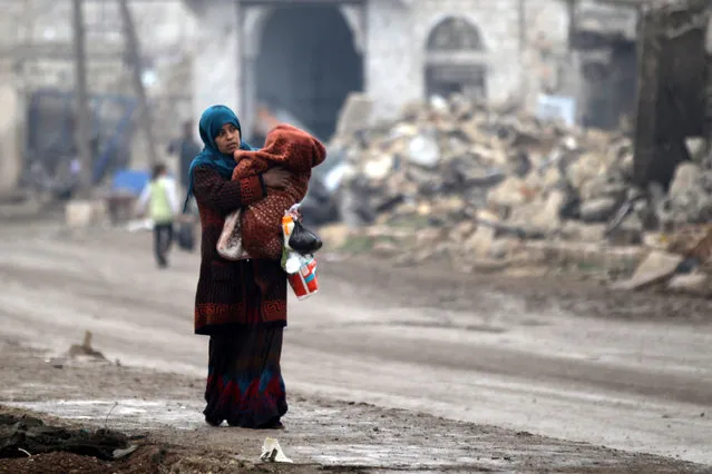 A woman carries a child as she walks near rubble of damaged buildings in al-Rai town, northern Aleppo countryside, Syria December 25, 2016. (Photo by Khalil Ashawi/Reuters)