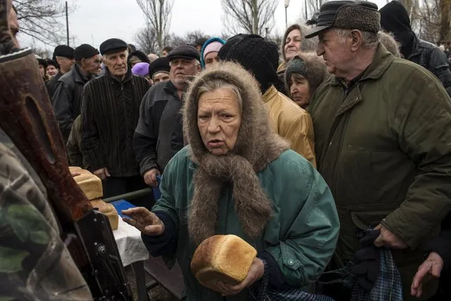 People queue for free bread distributed by pro-Russian rebels in the village of Chornukhyne near the town of Debaltseve, north-east from Donetsk, March 12, 2015. (Photo by Marko Djurica/Reuters)