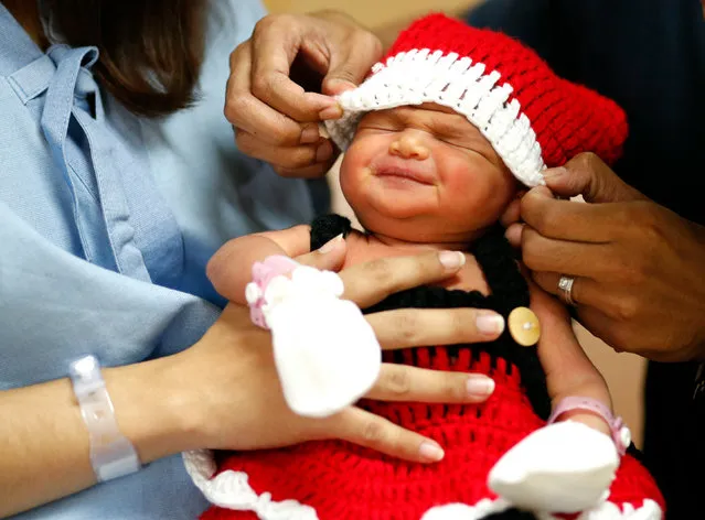 A newborn reacts while being dressed in a Santa Claus costume by her father and mother as part of the Christmas season celebrations at Paolo Memorial Hospital Chokchai 4 in Bangkok, Thailand, 21 December 2018. The hospital offers Santa Claus outfits to newborns as part of its delivery package to celebrate the Christmas season. (Photo by Rungroj Yongrit/EPA/EFE)