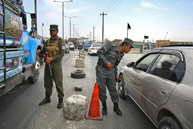 Afghan policemen stand guard at a checkpoint along the road in Kabul on August 14, 2021. (Photo by Wakil Kohsar/AFP Photo)