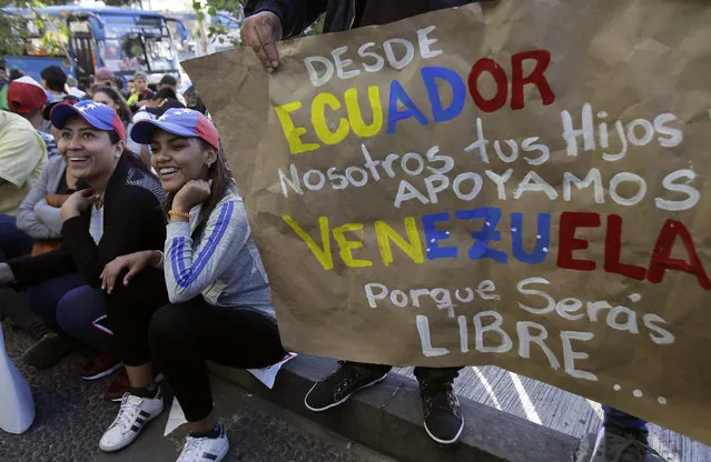 Venezuelan anti-government protesters gather outside their embassy with a sign that reads in Spanish “From Ecuador. We, your children, support Venezuela. Because you will be free...” in Quito, Ecuador, Wednesday, January 23, 2019. Venezuelan migrants are rallying in favor of Juan Guaido, head of Venezuela's opposition-run congress, who today declared himself interim president of Venezuela. (Photo by Dolores Ochoa/AP Photo)