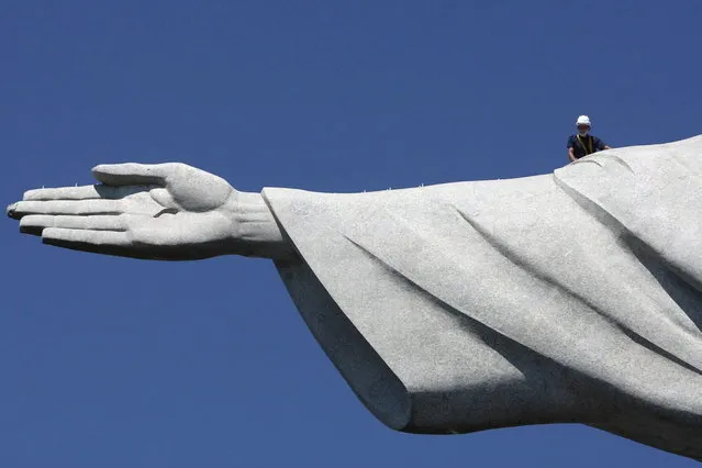 A worker inspects the Christ the Redeemer statue which was damaged during lightning storms in Rio de Janeiro January 21, 2014. Lightning strikes damaged the iconic figure's head and its right hand. The statue was hit on January 17 when a powerful electric storm swept through the city emitting more than 40,000 lightning strikes throughout the state of Rio de Janeiro. (Photo by Severino Silva/Reuters/Agência o Dia)