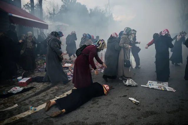 Women helps another woman who felt as Turkish anti-riot police officers launch tear gas to disperse supporters in front of the headquarters of the Turkish daily newspaper Zaman in Istanbul on March 5, 2016, after Turkish authorities seized the headquarters in a midnight raid. Turkish authorities were on March 5 in control of the newspaper staunchly opposed to President Recep Tayyip Erdogan after using tear gas and water cannon to seize its headquarters in a dramatic raid that raised fresh alarm over declining media freedoms. (Photo by Ozan Kose/AFP Photo)