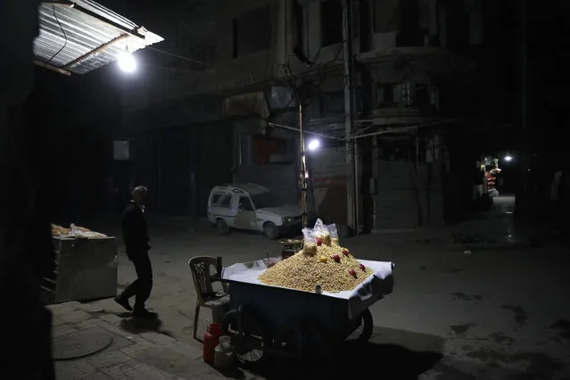 A Syrian man walks past a lupini beans cart in the rebel- held town of Douma, on the eastern outskirts of the capital Damascus, on January 25, 2017. (Photo by Abd Doumany/AFP Photo)