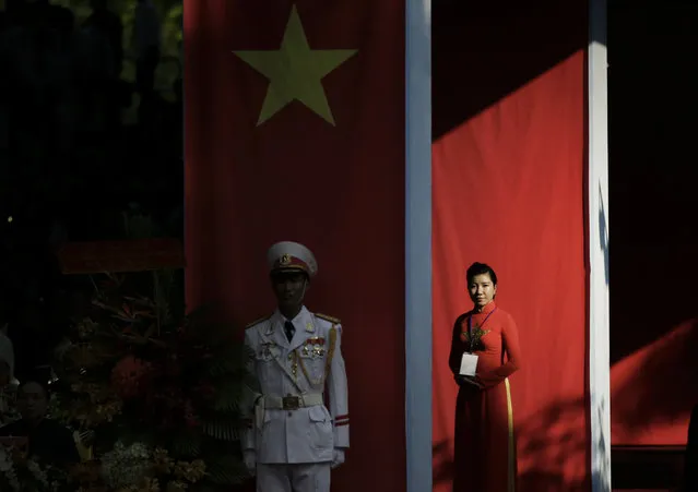 An usher in traditional Vietnamese dress called 'ao dai' prepares to greet guests prior to a parade celebrating the 40th anniversary of the end of the Vietnam War which is also remembered as the “Fall of Saigon”, in Ho Chi Minh City, Vietnam, Thursday, April 30, 2015. (Photo by Dita Alangkara/AP Photo)