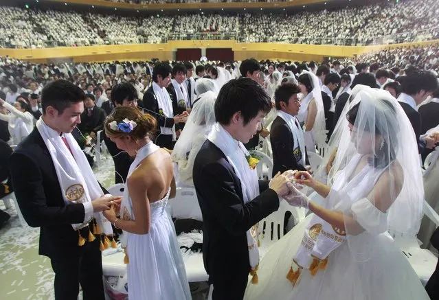Couples from around the world exchange their rings in a mass wedding ceremony at the CheongShim Peace World Center in Gapyeong, South Korea, Wednesday, February 12, 2014. (Photo by Lee Jin-man/AP Photo)
