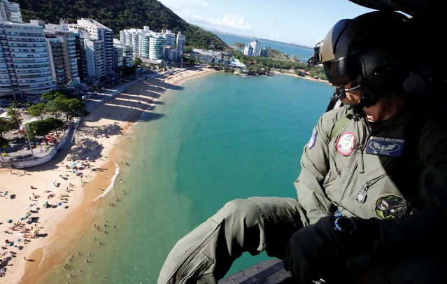 An air force soldier in a helicopter takes part in a patrol during a military police strike over wages, along Ponta beach in Vila Velha, Espirito Santo, Brazil, February 11, 2017. (Photo by Paulo Whitaker/Reuters)