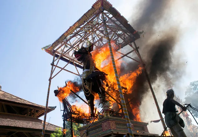 Balinese Hindu man burns bull coffins remaining of Ubud royal family members during a cremation ceremony in Gianyar, Bali, Indonesia, April 22, 2019. (Photo by Johannes P. Christo/Reuters)