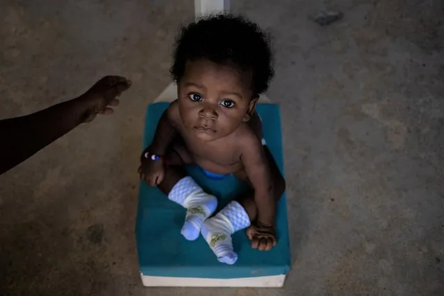 Five month old boy Peterson, who was suffering from a fever, sits on a scale after arriving to a clinic funded by St Louise De Marillac Daughters of Charity in the Cite Soleil shanty town of Port-au-Prince, Haiti on November 5, 2021. (Photo by Adrees Latif/Reuters)