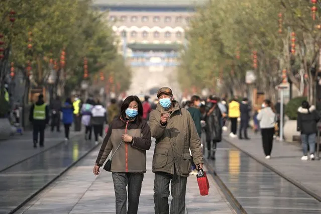 Visitors wearing face masks to help curb the spread of the coronavirus tour Qianmen Street, a popular tourist spot in Beijing, Wednesday, November 17, 2021. (Photo by Andy Wong/AP Photo)