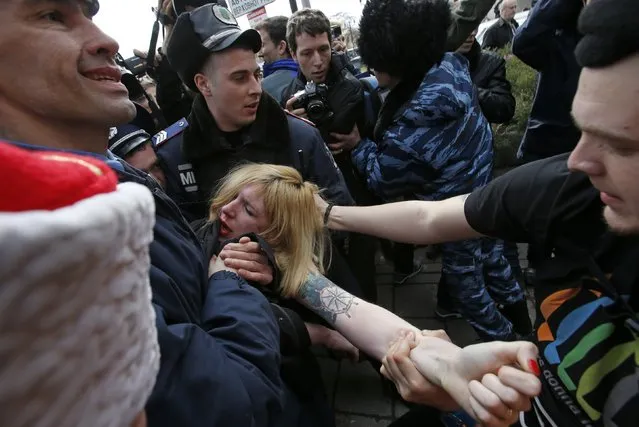 Members of Crimean self-defence units and Interior Ministry members block a topless activist from the Ukrainian feminist group Femen, who is taking part in an anti-war protest, near the Crimean parliament building in Simferopol, March 6, 2014. European Union leaders were set to warn but not sanction Russia on Thursday over its military intervention in Ukraine after Moscow rebuffed Western diplomatic efforts to persuade it to pull forces in Crimea back to their bases. (Photo by David Mdzinarishvili/Reuters)