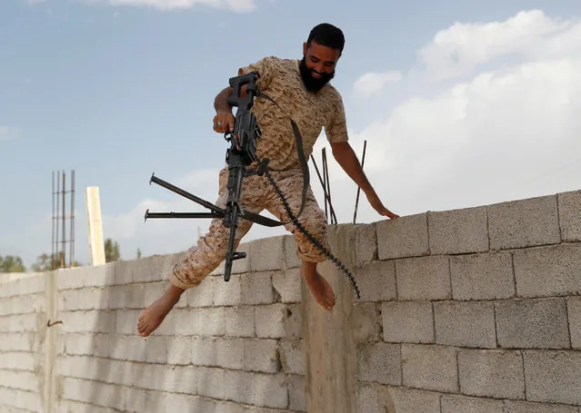 A member of the Libyan internationally recognised government forces jumps from a wall after he fired a rifle on the outskirts of Tripoli, Libya on May 12, 2019. (Photo by Goran Tomasevic/Reuters)