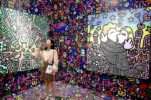 A visitor take photos of works by British artist Mr Doodle at Art Basel in Hong Kong on March 27, 2024. (Photo by Peter Parks/AFP Photo)