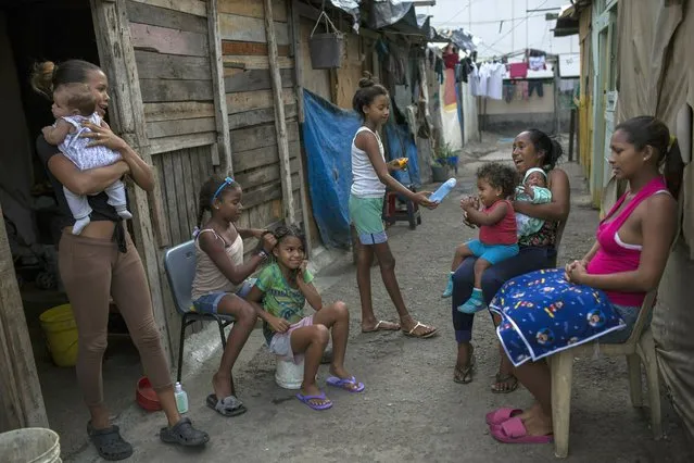 Families gather outside their home in the "Aguerridos Liberator" shanty town in Caracas, Venezuela, Thursday, May 9, 2019. (Photo by Rodrigo Abd/AP Photo)