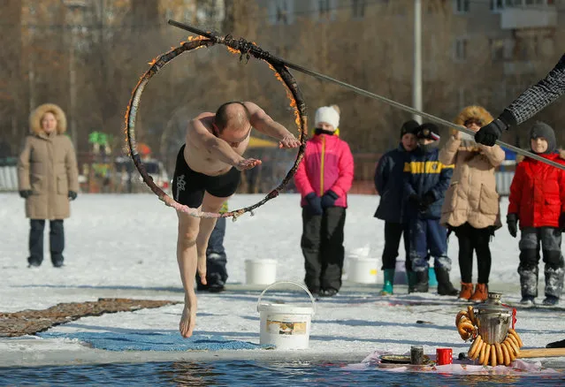 A man jumps into a pond during celebration of Maslenitsa, or Pancake Week, a pagan holiday marking the end of winter, in Podolsk, Russia, February 26, 2017. (Photo by Maxim Shemetov/Reuters)