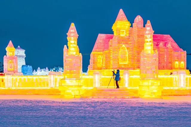 This photo taken on December 28, 2021 shows a man taking photos of ice sculptures at the Harbin Ice and Snow World in Harbin, in northeastern China's Heilongjiang province. (Photo by AFP Photo/China Stringer Network)