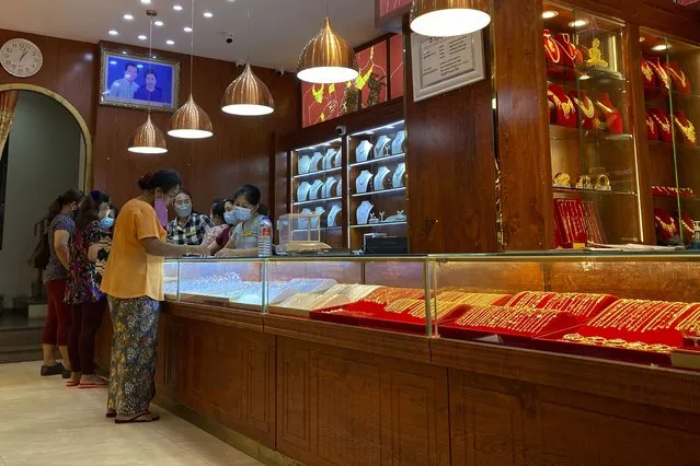 Customers browse items inside a jewelry store in Yangon, Myanmar on November 9, 2021. (Photo by AP Photo/Stringer)