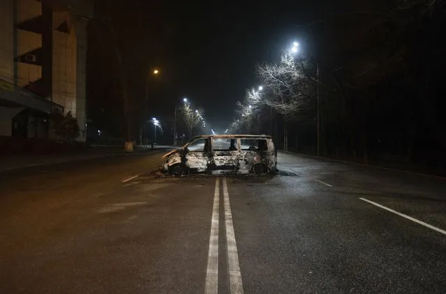A police bus, which was burned after clashes, remains in an empty street in Almaty, Kazakhstan, late Saturday, January 8, 2022. The office of Kazakhstan's president says about 5,800 people were detained by police during protests that burst into violence last week and prompted a Russia-led military alliance to send troops to the country. (Photo by Vasily Krestyaninov/AP Photo)