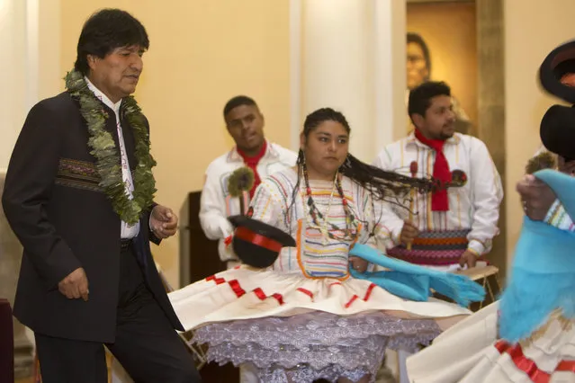 Bolivia's President Evo Morales, left, dances before the signing of a new coca law at the presidential palace in La Paz, Bolivia, Wednesday, March 8, 2017. Morales, who was rushed last week to Cuba for emergency treatment for problems with his vocal chords, reappeared Wednesday and against all recommendations spoke for almost an hour in defense of the controversial new law that would increase the amount of land for legal coca cultivation. (Photo by Juan Karita/AP Photo)