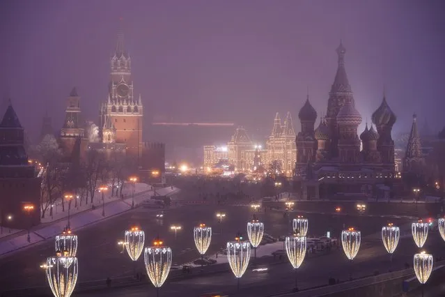 Red Square and the Kremlin are seen through evening fog in Moscow, Russia, Sunday, December 12, 2021. Presidents Joe Biden and Vladimir Putin spoke by phone on Thursday about the Russian troop buildup near Ukraine. It was a new round of leader-to-leader talks that come as the Kremlin has stepped up its calls for security guarantees and test fired hypersonic missiles to underscore its demands. (Photo by Alexander Zemlianichenko/AP Photo)