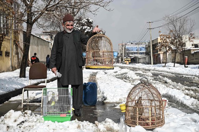 A bird vendor holds a cage with a bird on a sideroad after a heavy snowfall in Kabul on January 5, 2022. (Photo by Mohd Rasfan/AFP Photo)