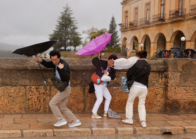 Tourists fight to hold their umbrellas during heavy rain and high winds, while they tour the city centre, as Storm Nelson hits Spain on Easter Sunday, the last day of Holy Week, in Ronda, Spain on March 31, 2024. (Photo by Jon Nazca/Reuters)