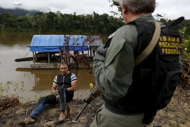 An agent of Brazil’s environmental agency detains a gold prospector who works as a diver in the illegal gold dredge on the shores of Uraricoera River, during an operation against illegal gold mining on indigenous land, in the heart of the Amazon rainforest, in Roraima state, Brazil April 15, 2016. (Photo by Bruno Kelly/Reuters)