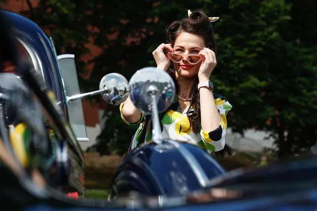 A woman straightens his sunglasses during the 2019 GUM Motor Rally featuring classic cars in Moscow, Russia on July 28, 2019. (Photo by Artyom Geodakyan/TASS via Getty Images)