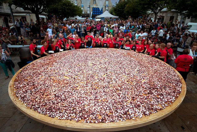 People prepare a giant octopus “tapa” to try to break a new world record in O Carballino in Galicia, northern Spain, 06 August 2019, on occasion of the celebration of the traditional octopus day on 11 August. (Photo by Brais Lorenzo/EPA/EFE)
