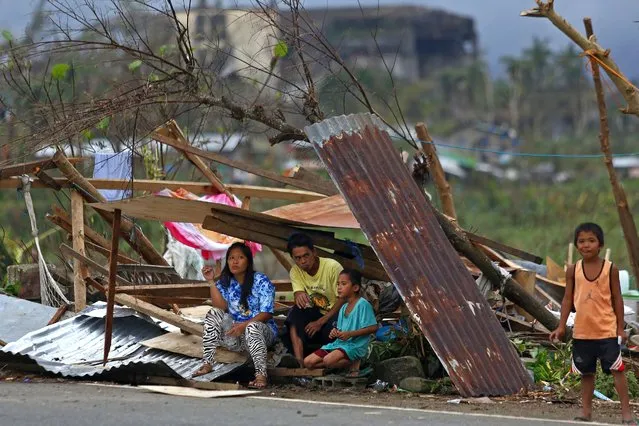 A family whose house was damaged, take shelter under a tree covered with iron sheets along a highway in Surigao City, Surigao del Norte province, on December 24, 2021, days after super Typhoon Rai devastated the city. (Photo by Ferdinandh Cabrera/AFP Photo)