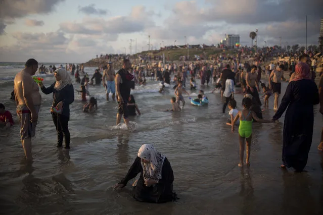 Muslims, many of whom are Palestinians from the West Bank, bathe in the Mediterranean Sea during the last day of the Eid al-Fitr holiday as the sun sets in Tel Aviv, Israel, Sunday, July 19, 2015. The three-day Eid al-Fitr holiday marks the end of the holy fasting month of Ramadan. One of the most important holidays in the Muslim world, Eid al-Fitr, is marked with prayers, family reunions and other festivities. (Photo by Ariel Schalit/AP Photo)