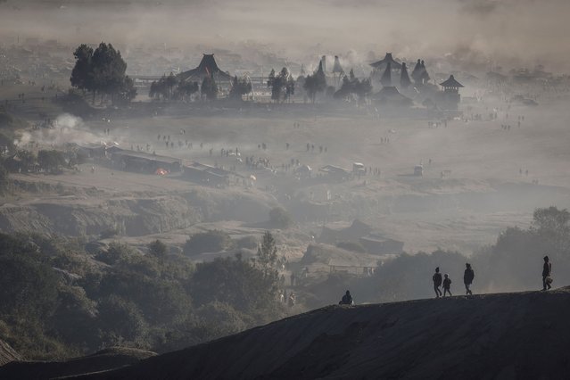 Luhur Poten Temple is surrounded by dust as Tenggerese Hindu worshippers and villagers gather at Mount Bromo's crater to throw their offerings, during the Yadnya Kasada festival in Probolinggo, East Java, Indonesia, on June 22, 2024. The festival has been held by the Tenggerese since the 13th century to express their devotion and gratitude to their ancestors and gods, thousands of people trek to the top of Mount Bromo (2,329m) and end their ritual by hurling offerings into the volcano's crater. “To respond to what the Almighty has conveyed through nature, the people must adapt and they should not forget to pray”, said Suyitno, a Tenggerese spiritual leader. (Photo by Willy Kurniawan/Reuters)