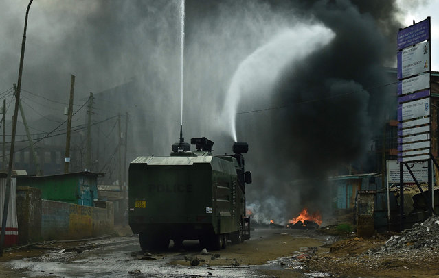 A police truck with a water cannon extinguishes a burning barricade in Kibera slum, Nairobi on May 23, 2016 during a demonstration of opposition supporters protesting for a change of leadership at the electoral commission ahead of a vote due next year. (Photo by Carl De Souza/AFP Photo)
