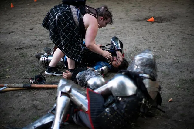 A man in full medieval armor is helped by his girlfriend after being hit in the head while taking part in a combat at Central Park in New York, U.S., August 14, 2021. (Photo by Eduardo Munoz/Reuters)