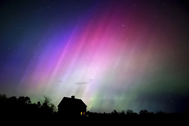 The northern lights flare in the sky over a farmhouse, late Friday, May 10, 2024, in Brunswick, Maine. (Photo by Robert F. Bukaty/AP Photo)