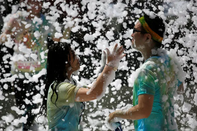 Participants play with foam bubbles during the Love Foam Run race in Hsinchu, Taiwan May 29, 2016. (Photo by Tyrone Siu/Reuters)